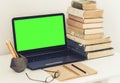 Green screen laptop, stack of old books, notebook and pencils on white table, education office concept background