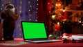 Green screen laptop standing on red table in room with christmas decorations. Place for advertising, New Year promotions Royalty Free Stock Photo
