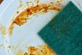 Green scrub sponge purely to food stain on white dish