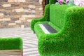 Green sculpture of grand piano with real white and black keyboard and special stool made from artificial grass. Urban