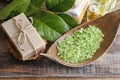 Green sea salt and bar of natural handmade soap on wooden table Royalty Free Stock Photo