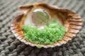 Green sea salt and pink crystal in a seashell on a gray knitted surface