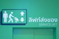 Green service elevator with working human and arrow sign in department store or office in urban area