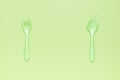 A green set of plastic forks and spoons on a green background. A place for your text. Flat lay Royalty Free Stock Photo
