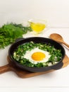 Green shakshuka. Fried eggs with fresh arugula, green onions, dill in a pan