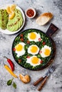 Green shakshuka with spinach, kale and peas. Healthy delicious breakfast with eggs, citrus salad, avocado. Top view, overhead Royalty Free Stock Photo