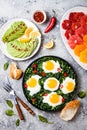 Green shakshuka with spinach, kale and peas. Healthy delicious breakfast with eggs, citrus salad, avocado. Top view, overhead Royalty Free Stock Photo