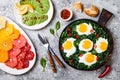 Green shakshuka with spinach, kale and peas. Healthy delicious breakfast with eggs, citrus salad, avocado. Top view, overhead Royalty Free Stock Photo