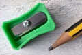 A green sharpener and a pencil on a white table. Royalty Free Stock Photo