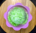 Top down view of lime green Hawaiian Shave ice, Shaved ice or snow cone dessert in a flower cup on a wooden table background.