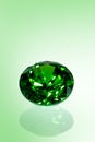 Green shiny emerald in front of green background, brilliant cut