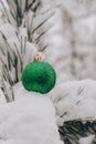 Green shiny trendy Christmas ball on snowy branch firs in winter forest. Winter holiday background. Copy space. Happy Royalty Free Stock Photo