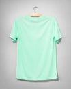 Green shirt hanging on cement wall. Empty clothing for design. Back view Royalty Free Stock Photo