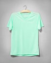 Green shirt hanging on cement wall. Empty clothing for design. Front view Royalty Free Stock Photo