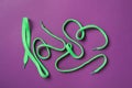 Green shoelaces on purple background, flat lay