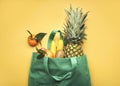 Green shopping bag with different fruits,pineapple, bananas, oranges, kiwis and apples