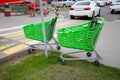 Green shopping carts near the pedestrian crossing in the background of a parking lot for cars. Royalty Free Stock Photo