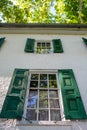 Green shutters on antique 15-pane windows of colonial American house.