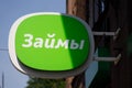 A green sign on the facade of the building with an inscription in Russian LOANS. credit institution