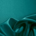Green silk satin. Wavy soft folds on the surface of shiny fabric. Luxurious teal background Royalty Free Stock Photo