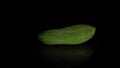 Green-skinned cucumber rotates on a black background.