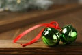 Green sleigh bells with red ribbon on wooden table, closeup Royalty Free Stock Photo