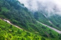 The green slopes of high mountains are hidden in clouds and fog. Melting snow in high mountains in summer