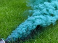 Green smoke from a smoke grenade pouring out over grass