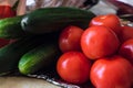 Green smooth cucumbers and red ripe tomatoes in a heap on a tray