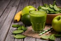 Green smoothie with apple, banana, avocado and spinach on a wooden rustic background.