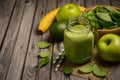 Green smoothie with apple, banana, avocado and spinach on a wooden rustic background.