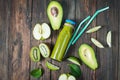 Green smoothie in bottl with avocado, apple and kiwi on white wooden background.