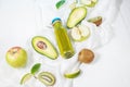 Green smoothie in bottl with avocado, apple and kiwi on white wooden background