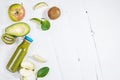 Green smoothie in bottl with avocado, apple and kiwi on white wooden background.