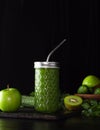 Green smoothie in a glass glass on a black background. Kiwi, apples,cucumbers and greens. Cooking healthy food. Zero weist, a