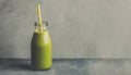 Green smoothie in glass bottle with paper straw. Tasty and healthy drink