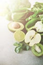 Green smoothie in glass jar with fresh organic green vegetables and fruits on grey background. Spring diet, healthy raw