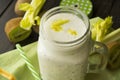 Green smoothie in a glass jar with lid and a straw, celery and kiwi over dark wooden background Royalty Free Stock Photo