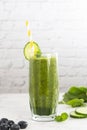 Green smoothie glass with spinach, banana blueberry, cucumber, avocado, bright kitchen background Royalty Free Stock Photo