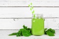 Green smoothie with kale and spinach in a mason jar with ingredients on a white wood background Royalty Free Stock Photo