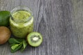 Green smoothie with kiwi fruit, cucumber, mint and parsley on old grey wooden desk