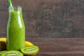 Green smoothie made of kiwi fruit and banana in a glass bottle with fresh fruits on rustic wooden background. Healthy Royalty Free Stock Photo