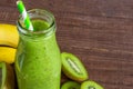 Green smoothie made of kiwi fruit and banana in a glass bottle with fresh fruits on rustic wooden background. Healthy Royalty Free Stock Photo