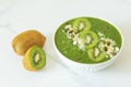 Green smothie bowl with kivi, decorated with seeds and nuts, close up