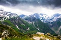 Green and snowy mountains with dark storm clouds above Royalty Free Stock Photo