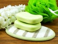 Green soap bar and plastic bath puff on wooden background Royalty Free Stock Photo