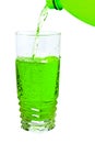 Green soda in a tall glass, pour from the bottle