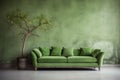 Green sofa against grunge distressed painted stucco wall and wooden decorative tree trunk. Minimalist home interior design