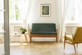 Green sofa with dark, wooden frame and a comfy yellow armchair i