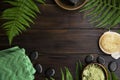 Green spa top view setting with fern leaves on wooden background with copy space, massage stones, green towel, clay powder Royalty Free Stock Photo